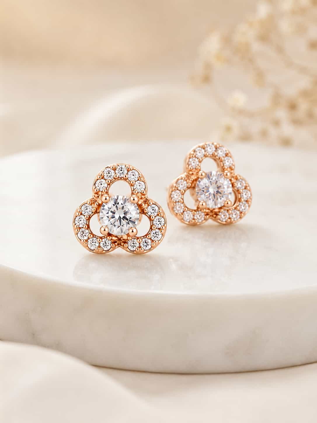Close-up of rose gold floral halo stud earrings with round centre stones and sparkling three-petal design