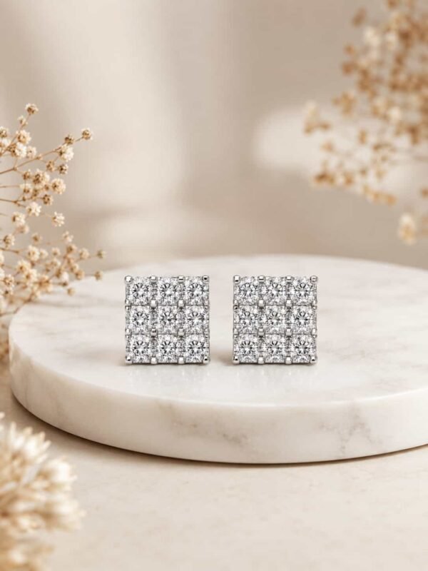 Platinum polished square cluster stud earrings displayed on cream marble pedestal