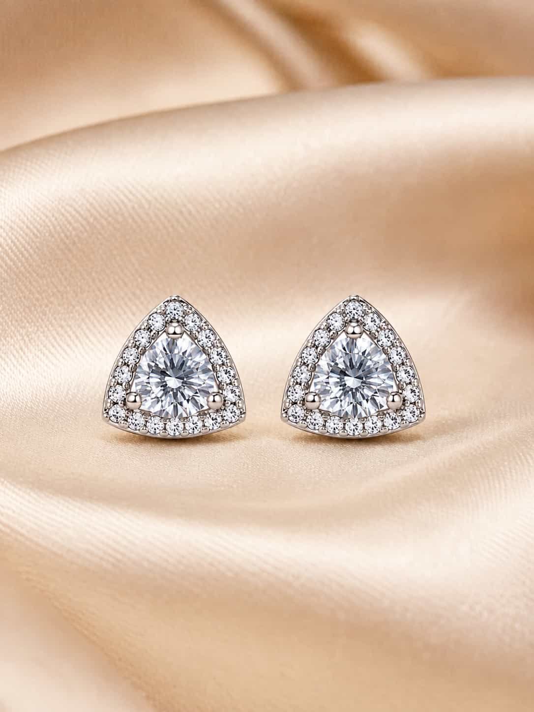 Celeste triangle halo sparkle stud earrings displayed on champagne satin