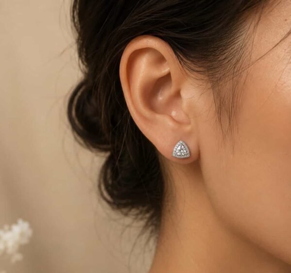 Woman wearing Celeste platinum polished triangle halo stud earring
