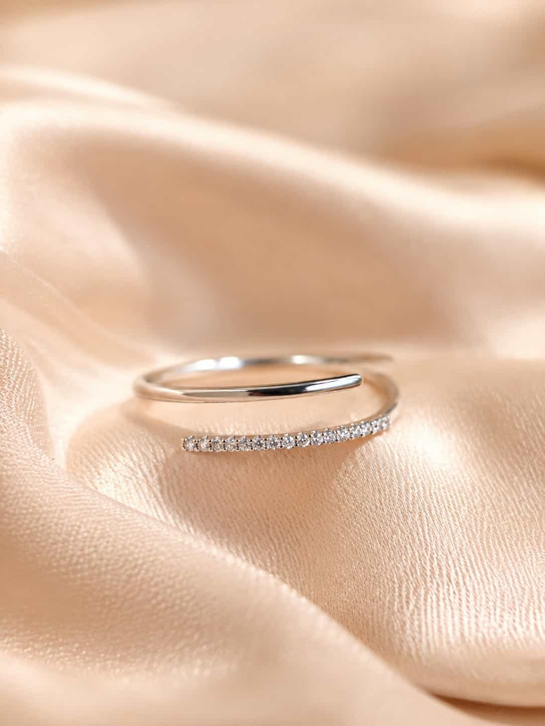 Naira platinum-polished double-row open wrap ring with sparkling clear stones displayed on champagne satin