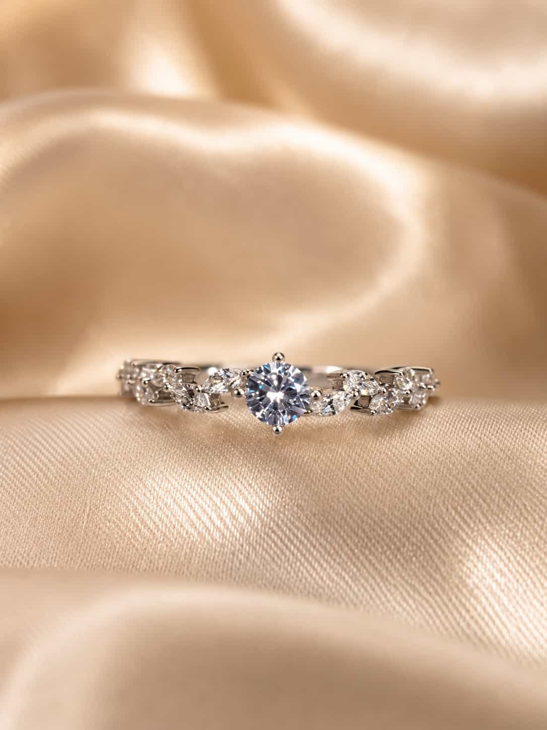 Fiora floral solitaire-style ring displayed on champagne satin with round centre and marquise side stones in focus