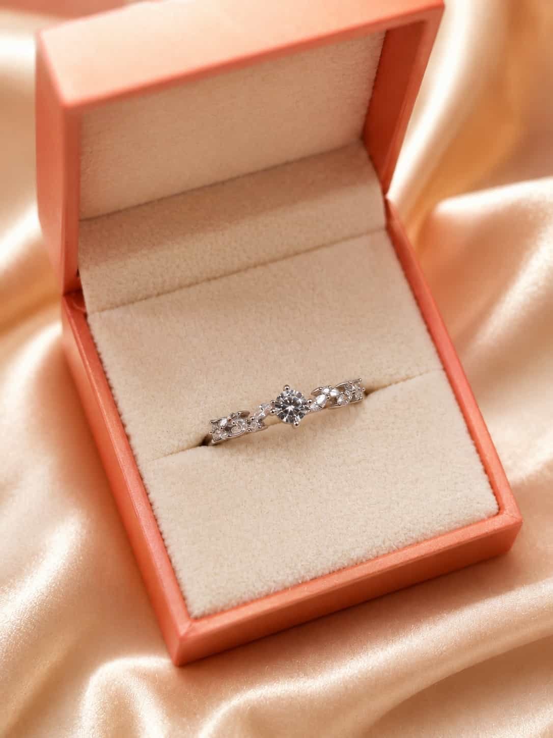 Fiora floral solitaire ring presented inside an orange jewellery gift box on champagne satin