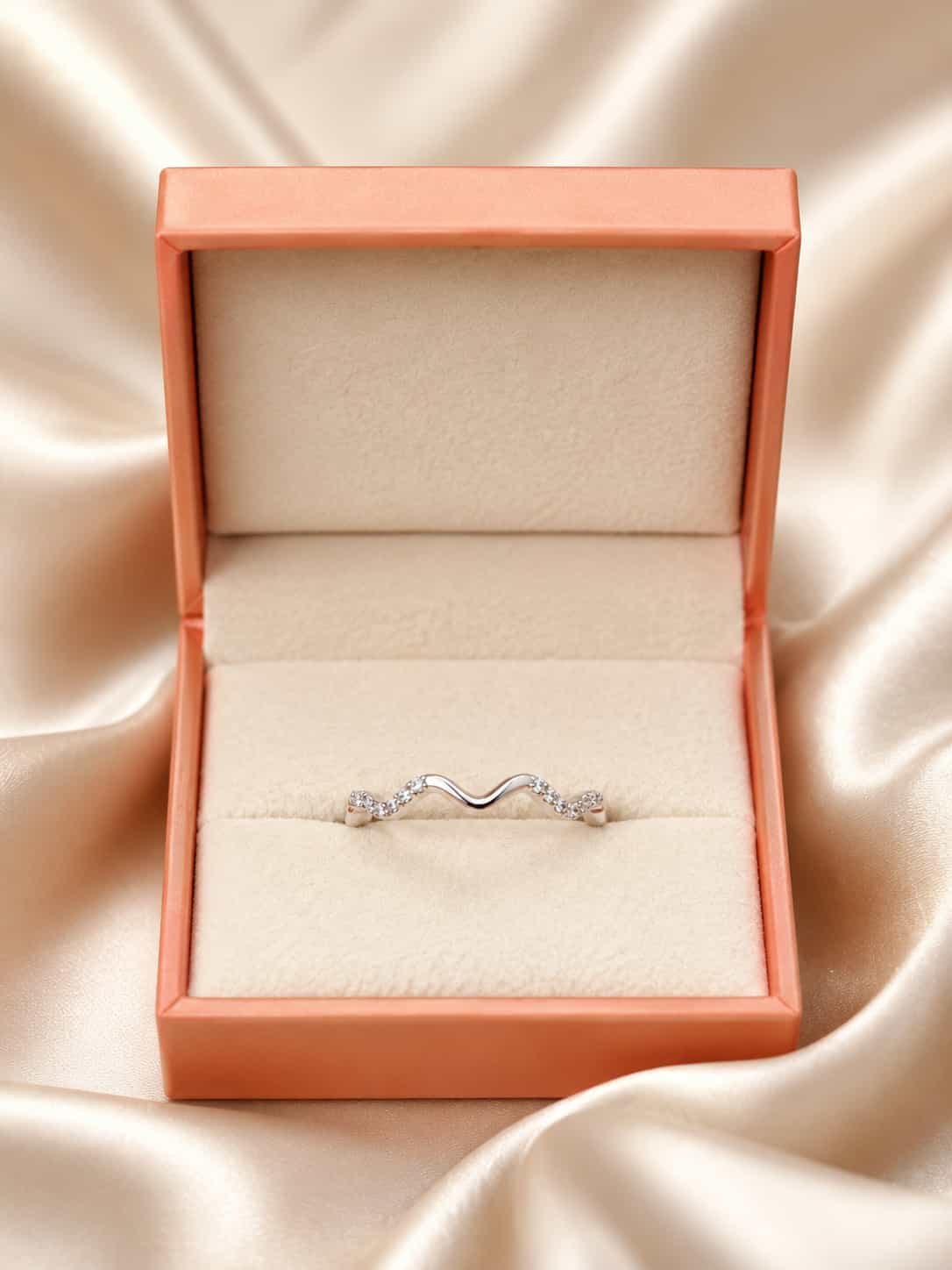 Serena wave sparkle ring presented inside an orange jewellery gift box on champagne satin