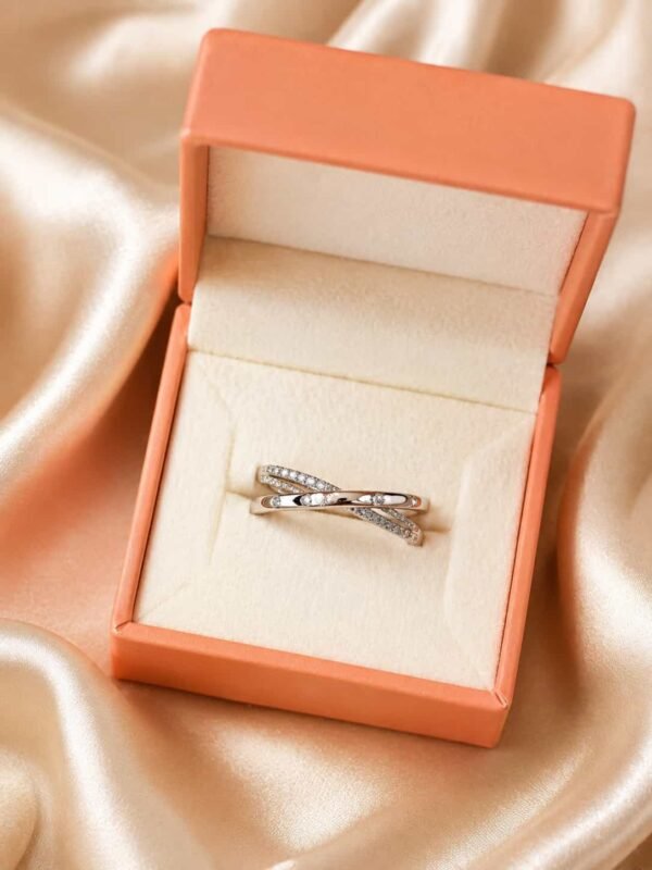 Elara criss-cross sparkle ring presented inside an orange jewellery gift box on champagne satin