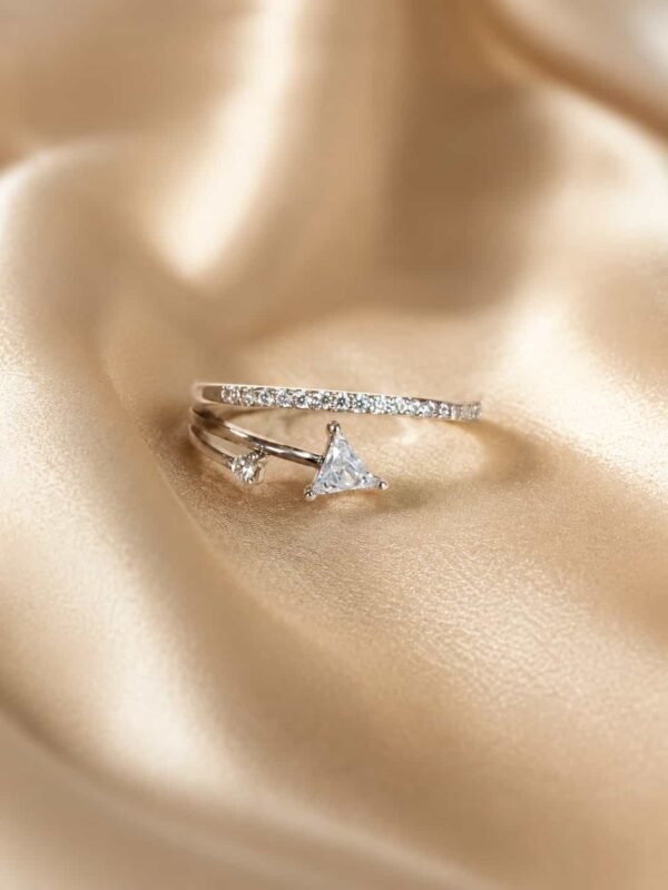 Evara triangle sparkle open ring displayed on champagne satin with its platinum-polished curved band in focus