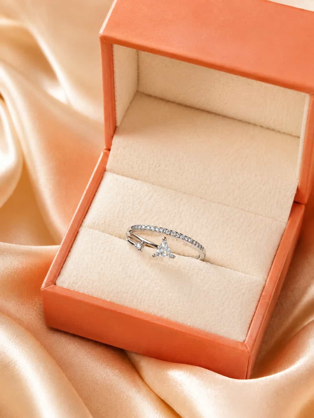 Evara triangle sparkle open ring presented inside an orange jewellery gift box on champagne satin