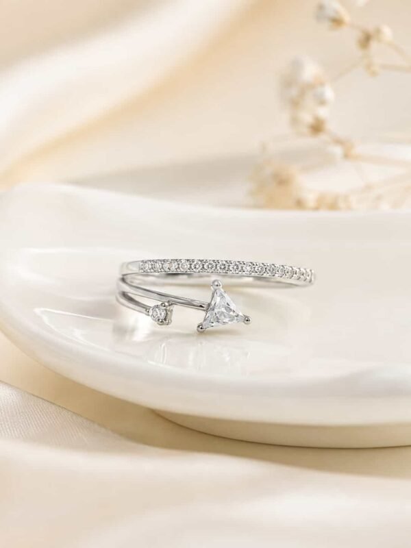 Close-up of the Evara triangle open ring with a clear triangle stone and sparkling band on a white ceramic tray