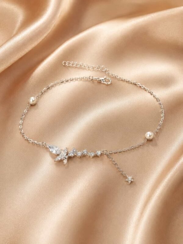Butterfly pearl sparkle bracelet with crystal trail and dangling star charm displayed on champagne satin