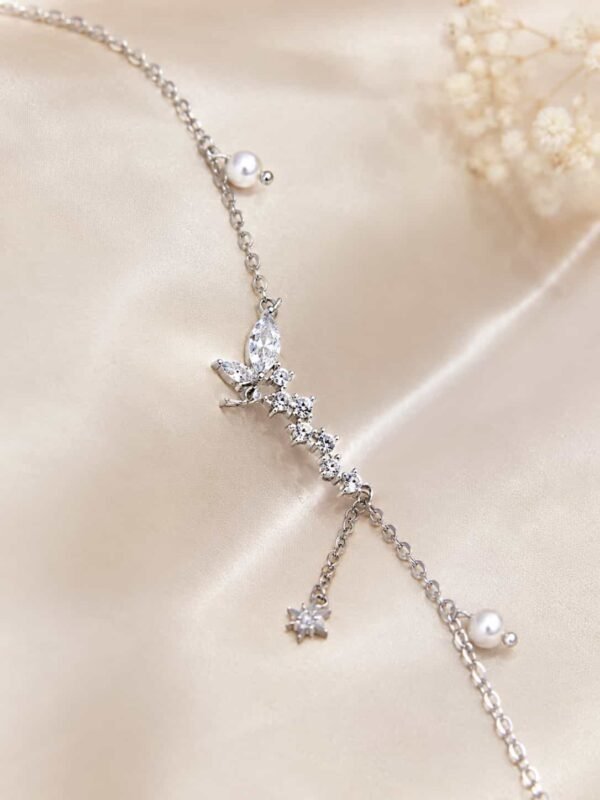 Close-up of sparkling butterfly bracelet with marquise clear stones, pearl accents and dangling star charm