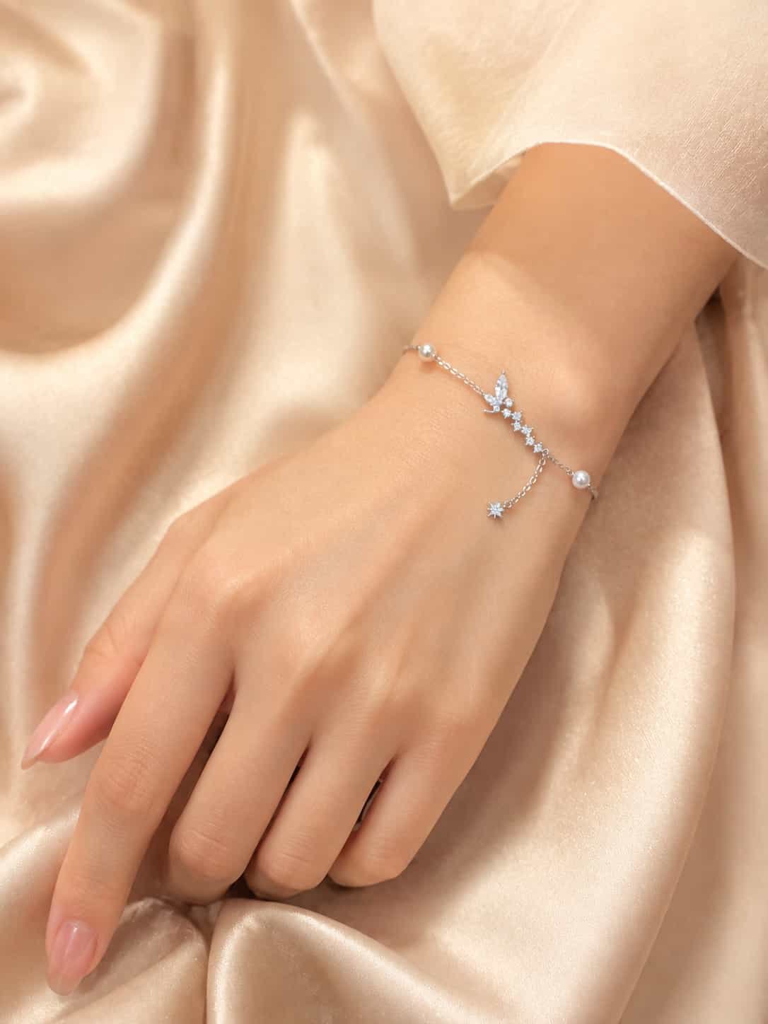 Woman wearing Celestia butterfly and pearl sparkle bracelet with delicate star charm on wrist