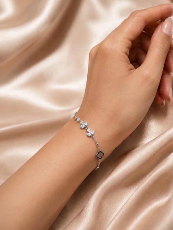 Woman wearing delicate silver-tone butterfly bracelet with sparkling stones and black clover charm